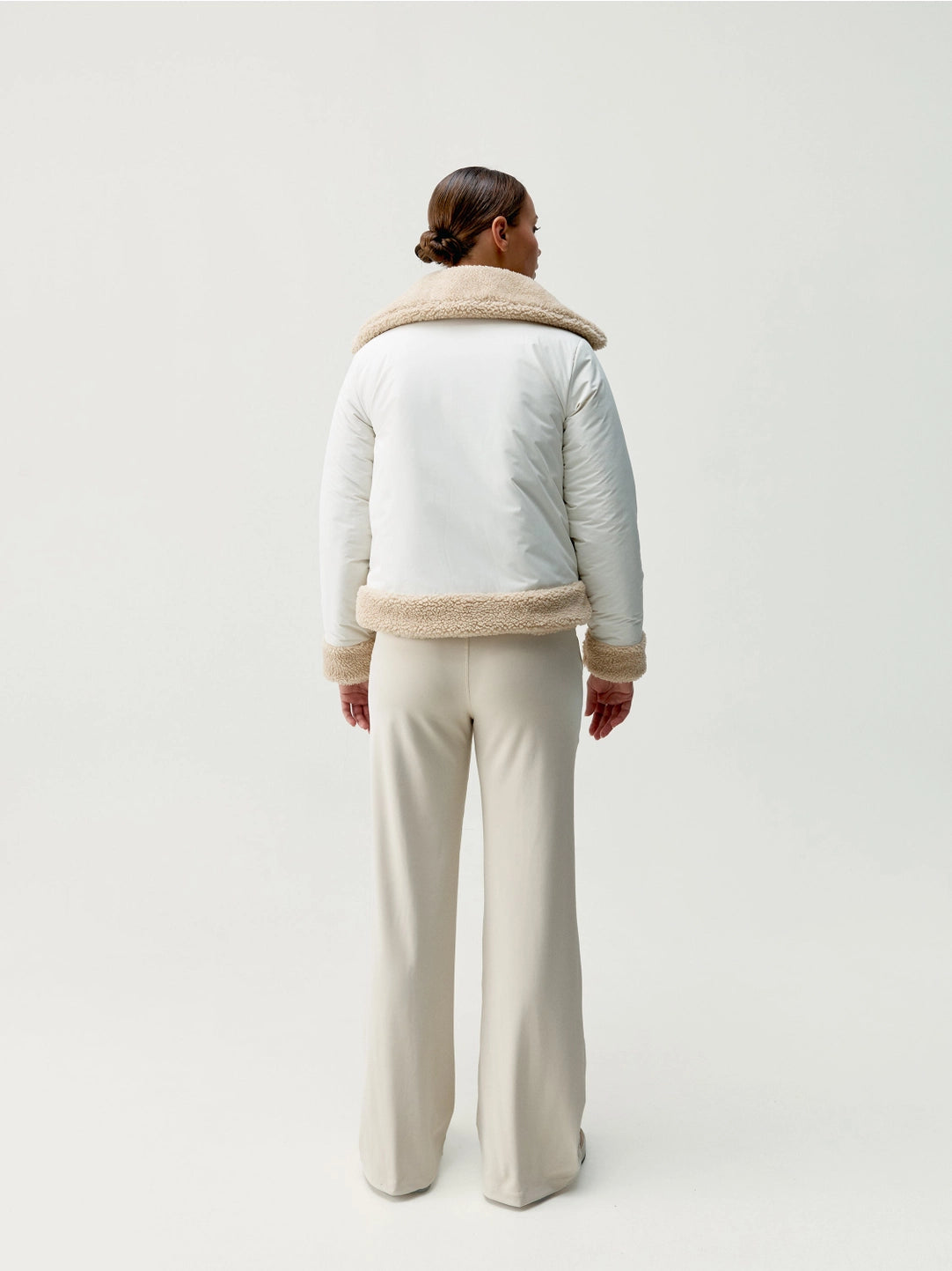 Modell med vit jacka bakifrån helkropp