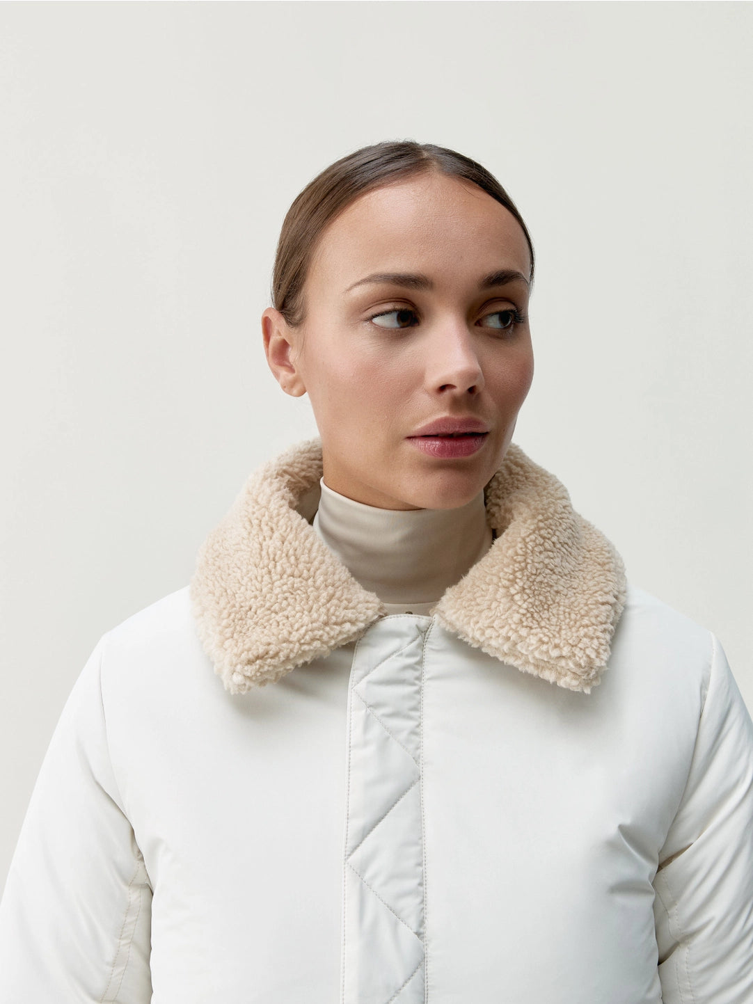 Närbild på modell med vit jacka och krage