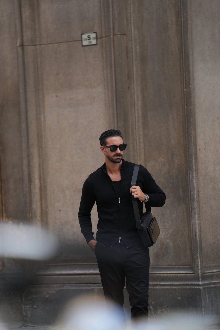 Manlig modell med väska och svart ziptröja